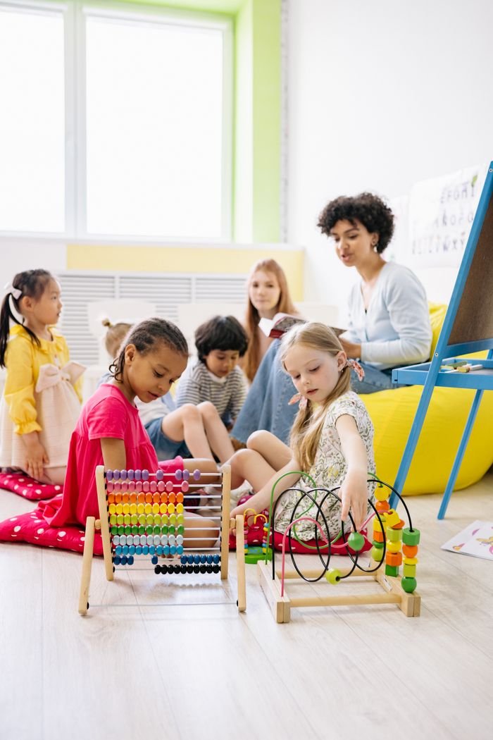 Preschool children with a teacher engaging in educational activities in a bright classroom.